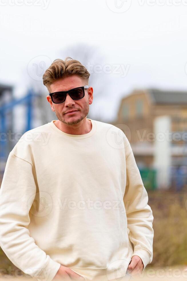 a atraente jovem homem com uma branco camisa e oculos de sol foto