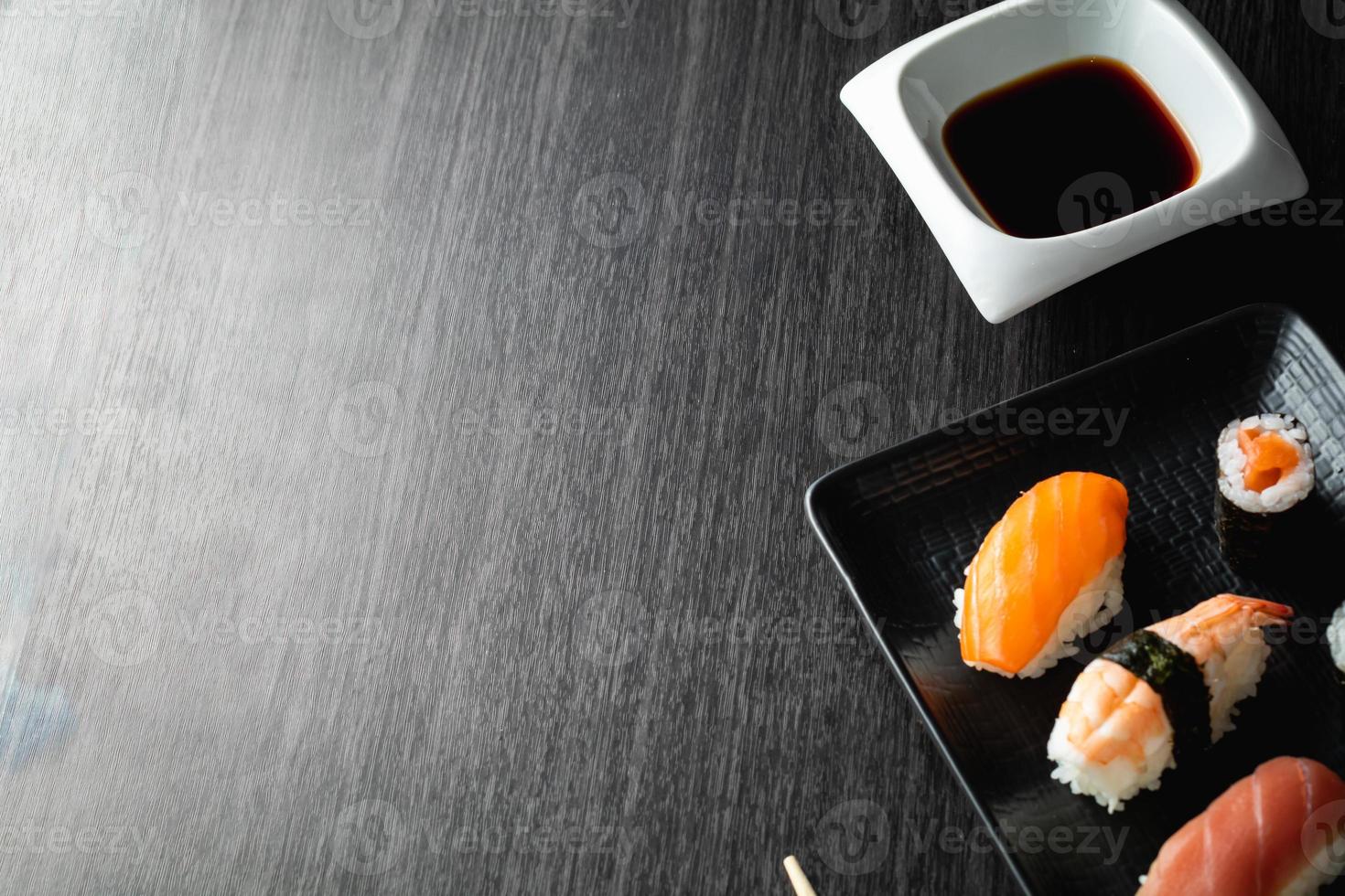 sushi elegante na mesa de madeira. um pouco de nigiri, com molho de soja e pauzinho foto