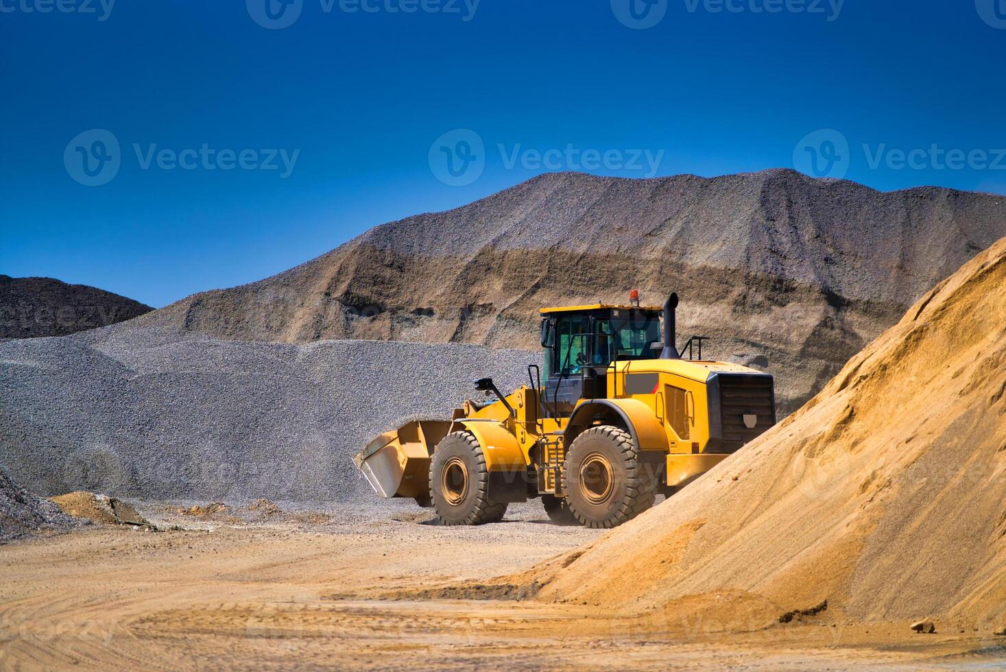 manutenção do amarelo escavadora em uma construção local contra azul céu. ressurgindo roda carregador às caixa de areia durante terraplenagem trabalho foto