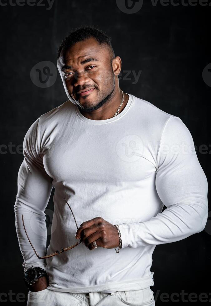 atraente muscular homem dentro branco camisa posando para Câmera. sexy bonito pessoa em Sombrio fundo. foto