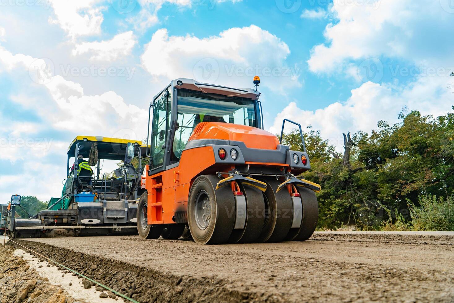 máquina para batendo a terra e rolo compressor para asfalto corre através a estrada dentro a verão foto