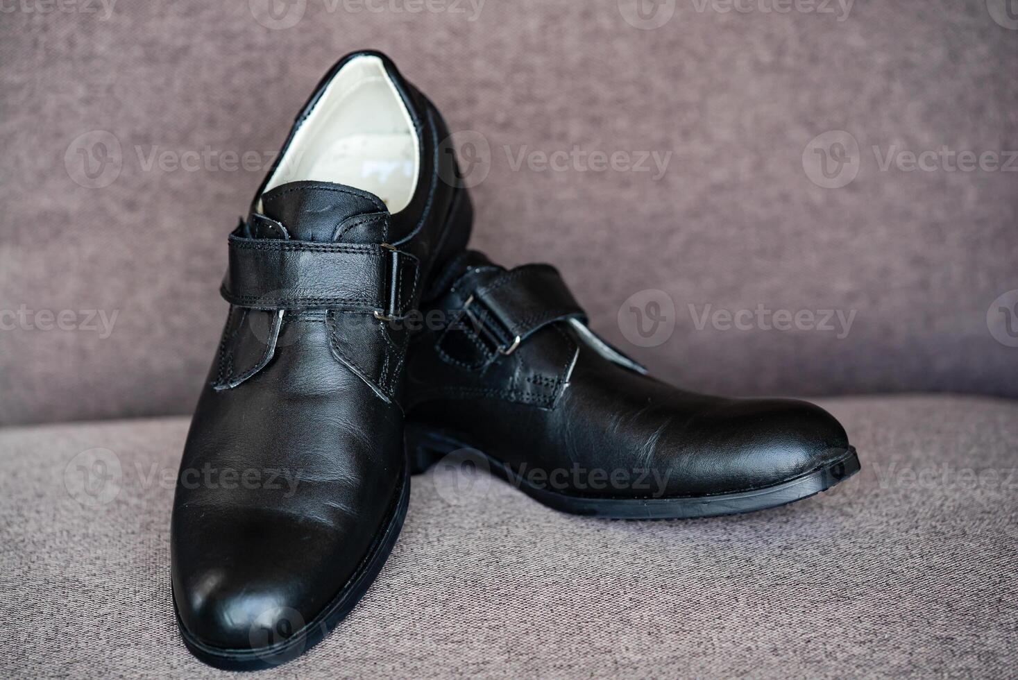 Preto couro sapatos para a Garoto isolado em a cinzento fundo. clássico sapatos com velcro para escola. fechar-se foto