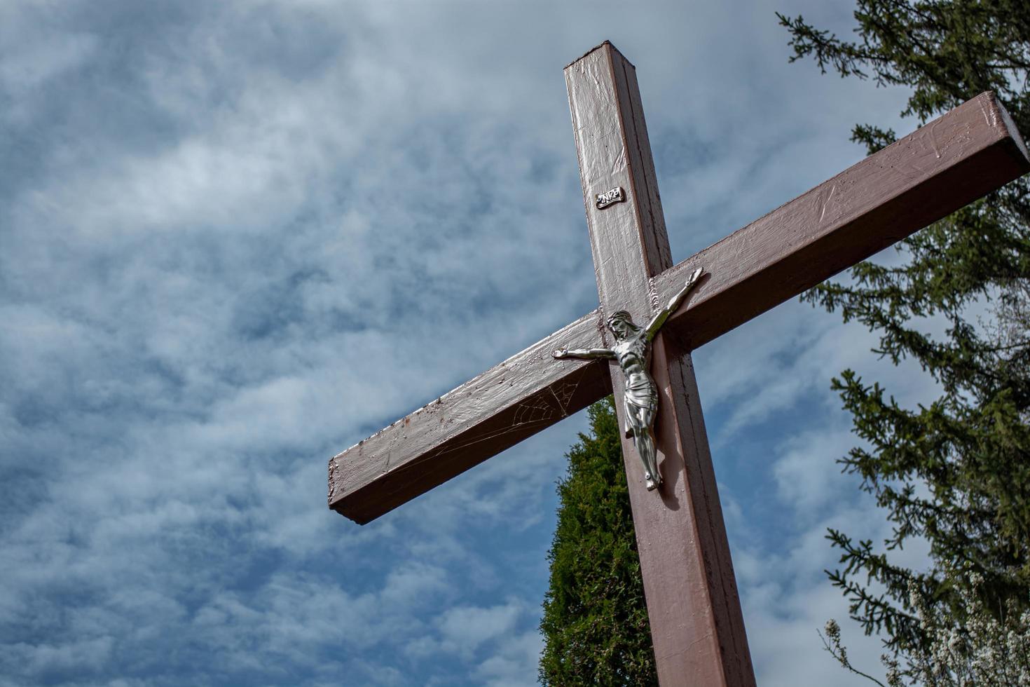 cruz de metal com jesus em um fundo de nuvens. foto
