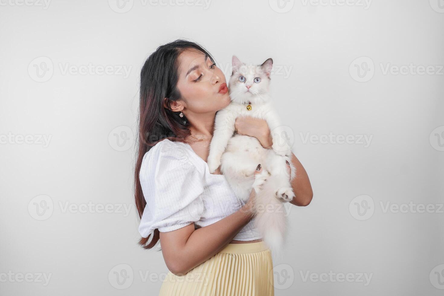 retrato do jovem ásia mulher segurando fofa boneca de pano gato com azul olhos. fêmea abraçando dela fofa grandes cabelo gatinha isolado de branco fundo. adorável doméstico animal conceito. foto