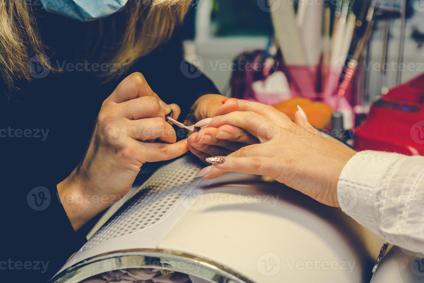 manicuro aplicando vermelho unha verniz. manicure mestre pintura fêmea dedo com fechar acima. manicure e dedos Cuidado. foto