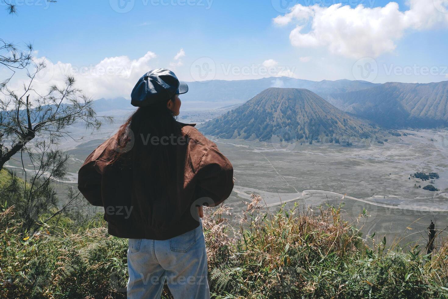 a ásia menina em pé em uma Colina rastrear dentro bromo, desfrutando Visão do bromo, uma Maravilhoso cenário dentro dramático Colina foto