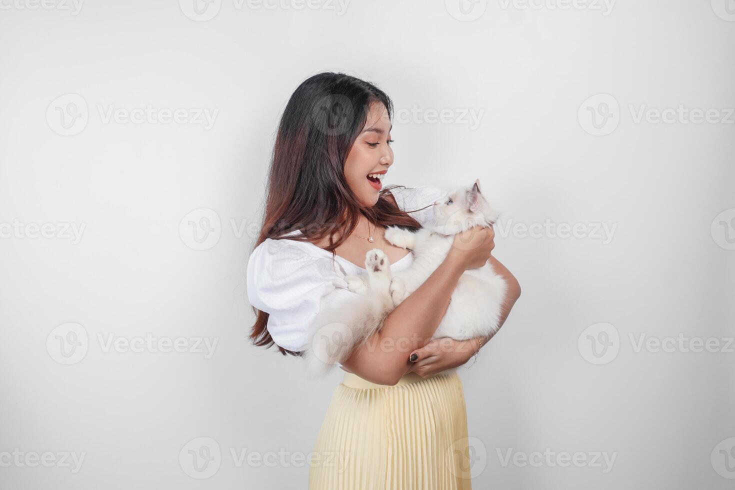 retrato do jovem ásia mulher segurando fofa boneca de pano gato com azul olhos. fêmea abraçando dela fofa grandes cabelo gatinha isolado de branco fundo. adorável doméstico animal conceito. foto