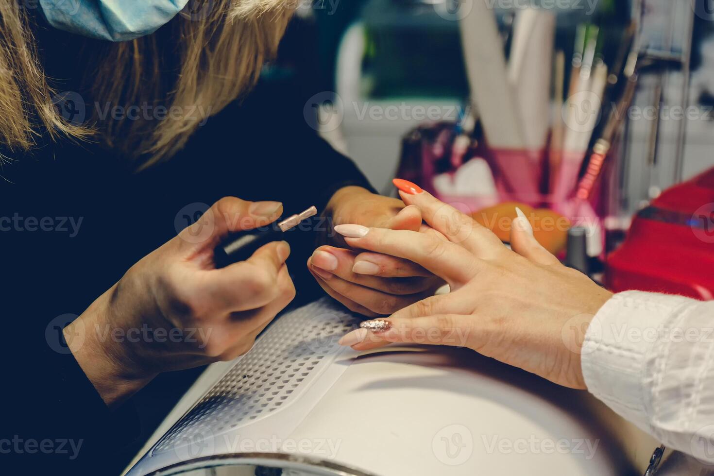 manicuro aplicando vermelho unha verniz. manicure mestre pintura fêmea dedo com fechar acima. manicure e dedos Cuidado. foto