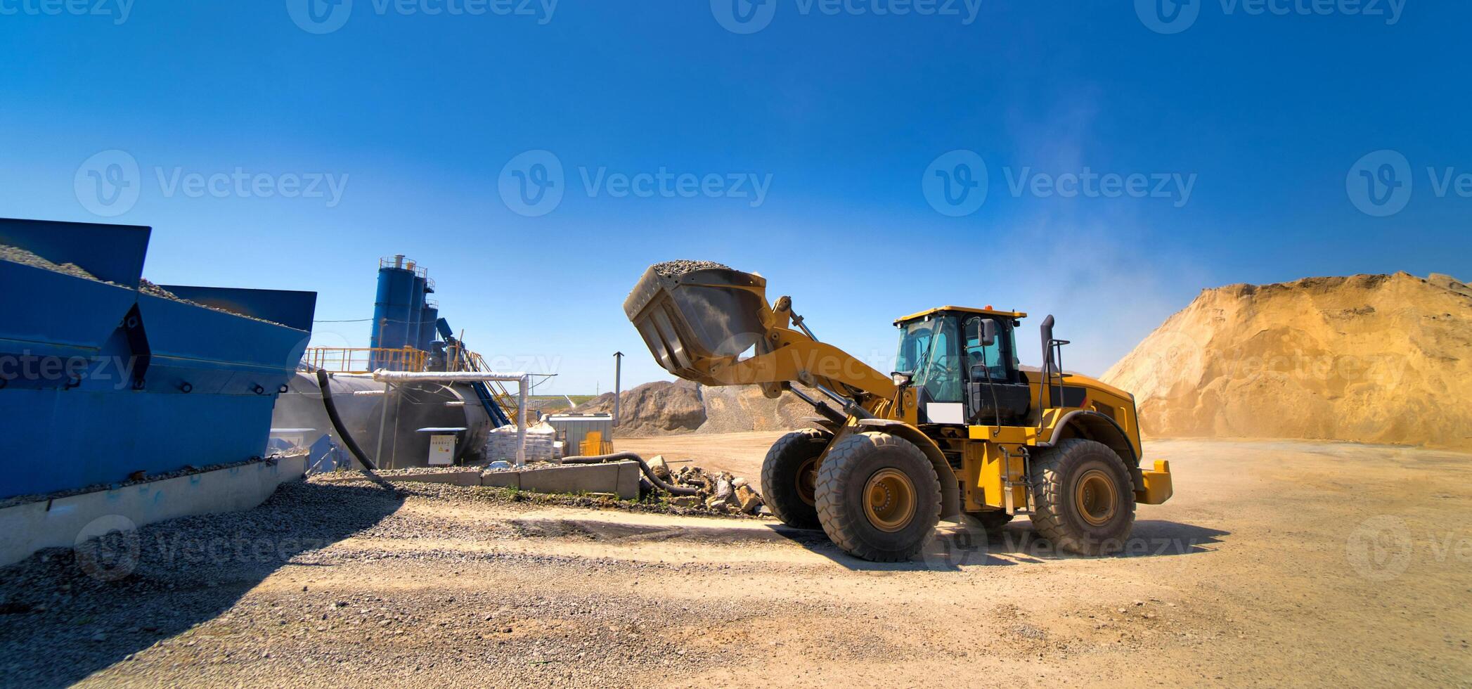 amarelo escavadora enquanto limpeza quintal do industrial espaço. seletivo foco. industrial zona. azul céu fundo. foto