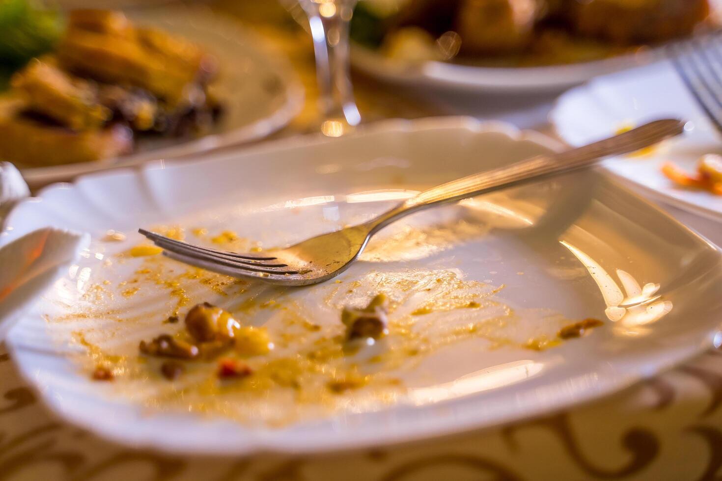 sujo esvaziar prato com garfo em a mesa. sobras do Comida em uma prato e uma garfo depois de a festa dentro a restaurante. fechar acima. foto