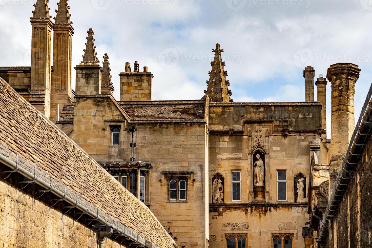 histórico pedra edifícios com ornamentado chaminés e gótico arquitetura debaixo uma nublado céu dentro Oxford, Inglaterra. foto