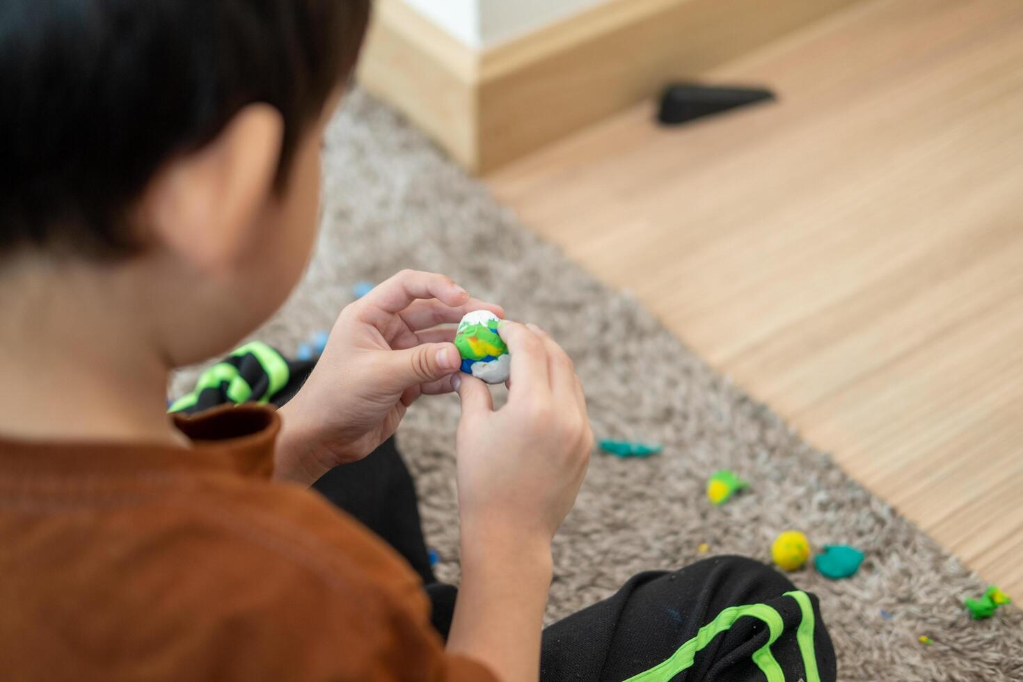 ásia Garoto jogando com plasticina dentro a quarto foto