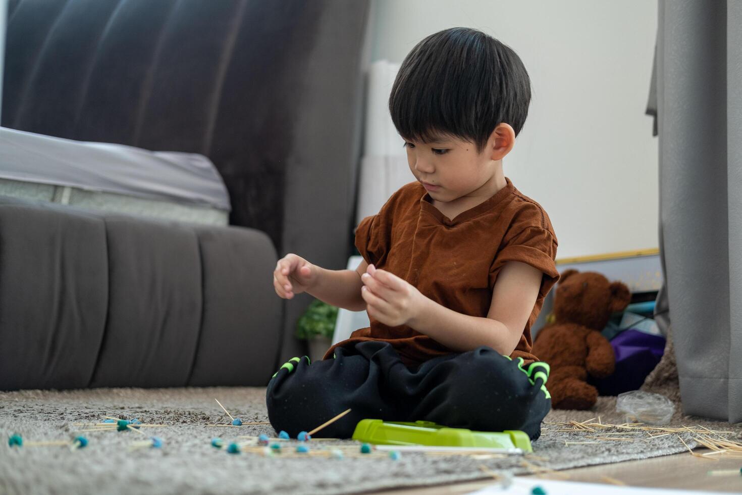 ásia Garoto jogando com plasticina dentro a quarto foto