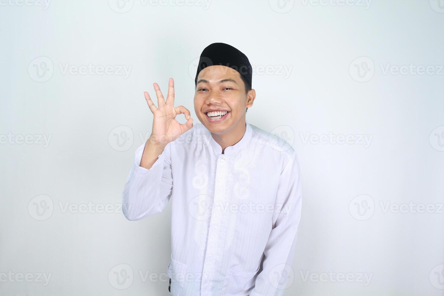 sorridente ásia homem muçulmano mostrar Está bem sinais isolado em branco fundo foto