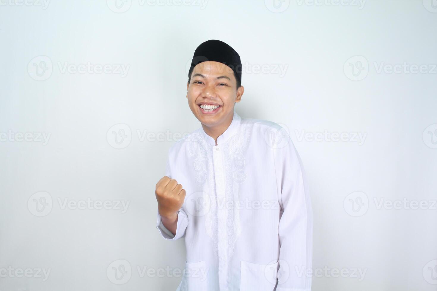 feliz muçulmano ásia homem levantando punho mostrar vitória gesto dentro eid Mubarak celebração isolado em branco fundo foto