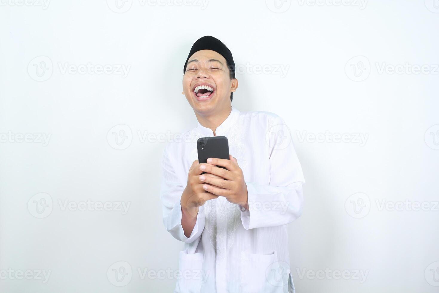 alegre ásia muçulmano homem rindo enquanto segurando telefone isolado foto