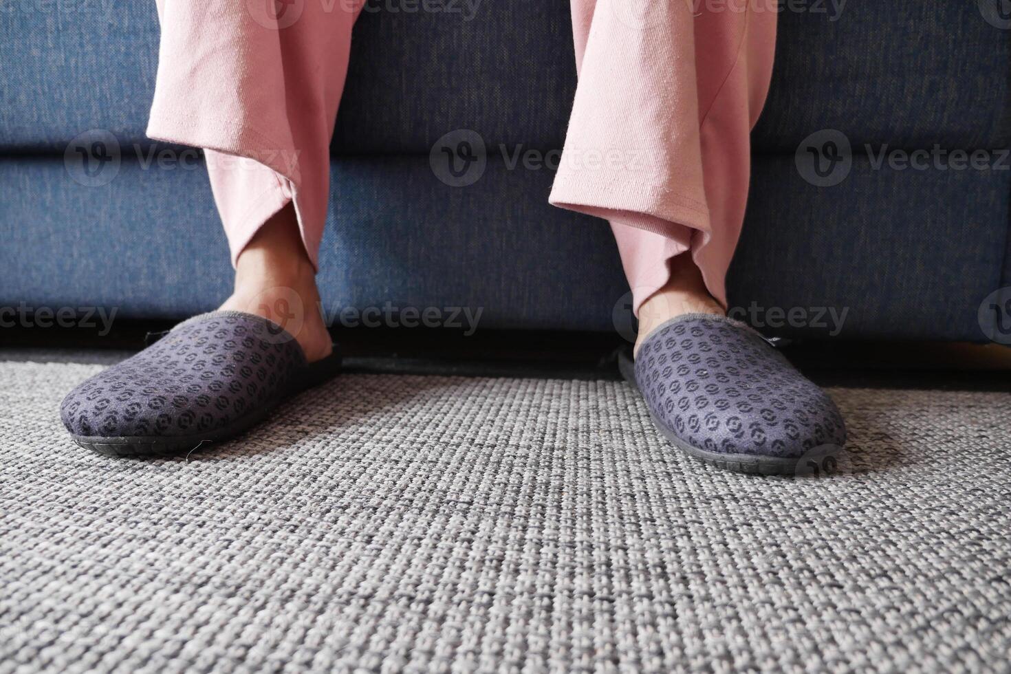 mulheres com cinzento chinelos é sentado em uma sofá foto