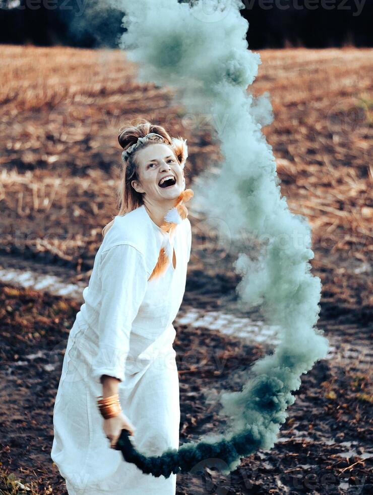 alegre jovem mulher com palhetas danças dentro colori fumaça dentro uma campo foto