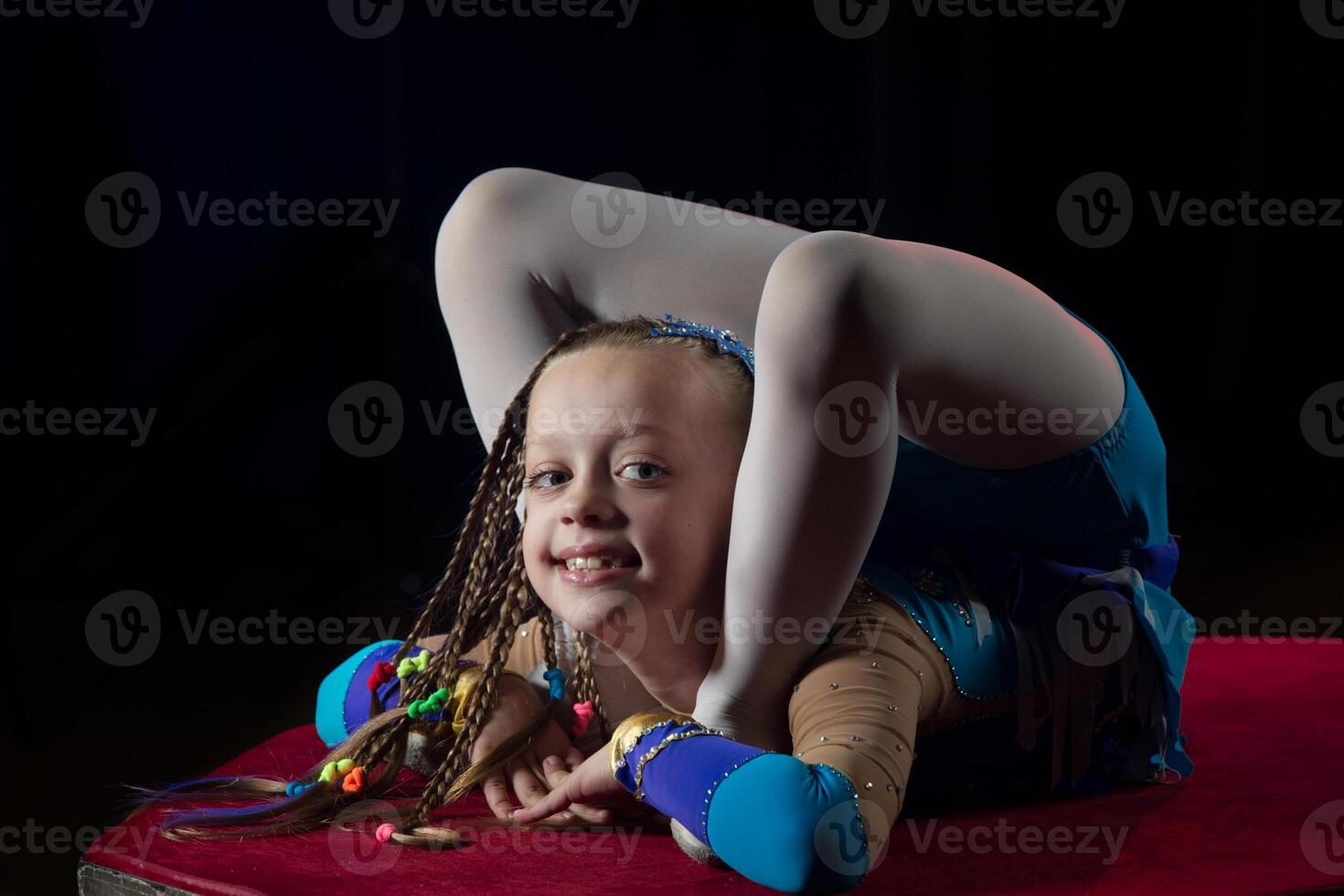 uma menina com uma flexível corpo. executa uma circo artista. circo ginasta. balanceamento agir. a criança executa a acrobático truque foto