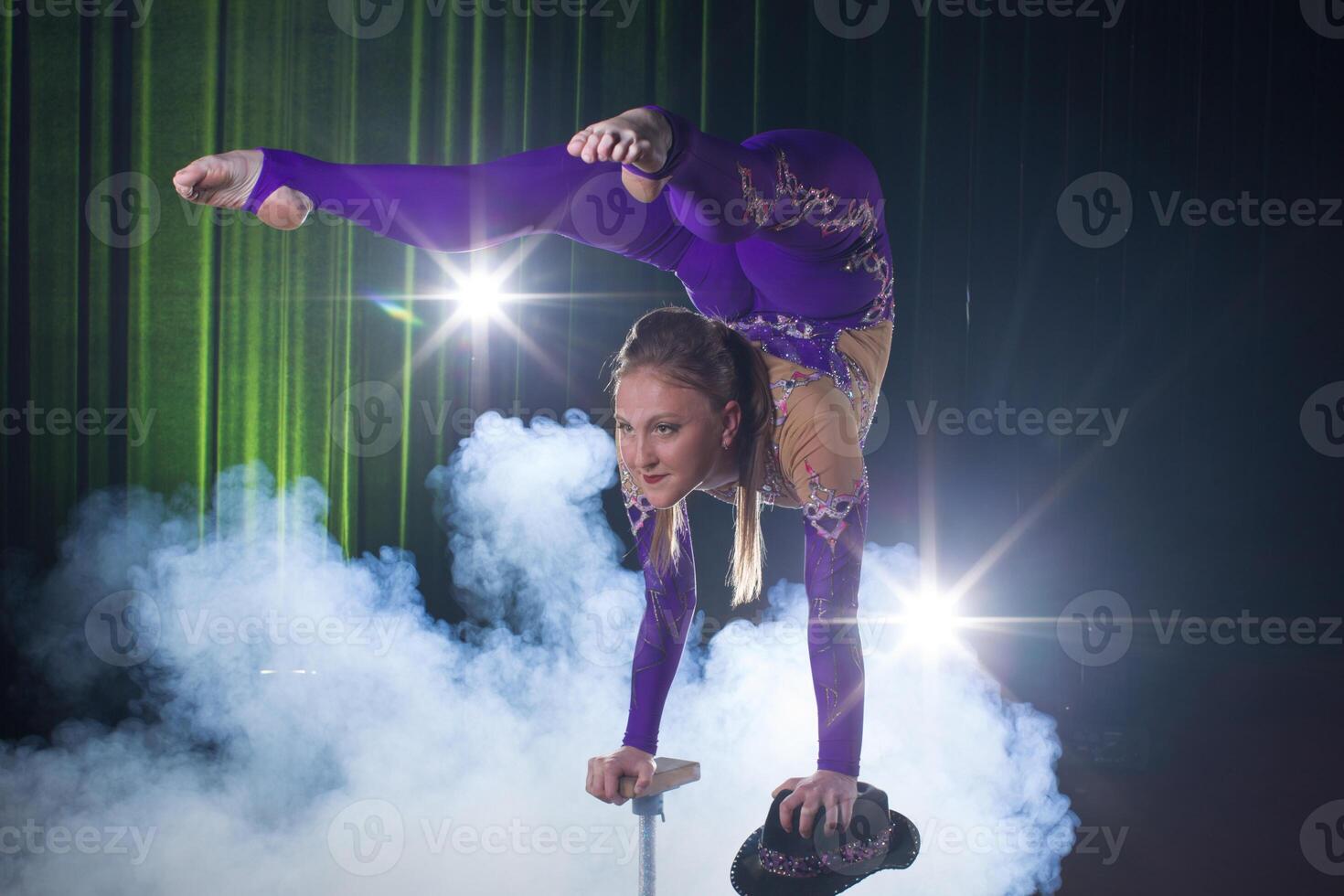 circo atriz executa a número dentro uma lindo fumaça. manual equilíbrio em bengalas. flexível menina corpo.desempenho do a ar ginasta dentro uma circo foto