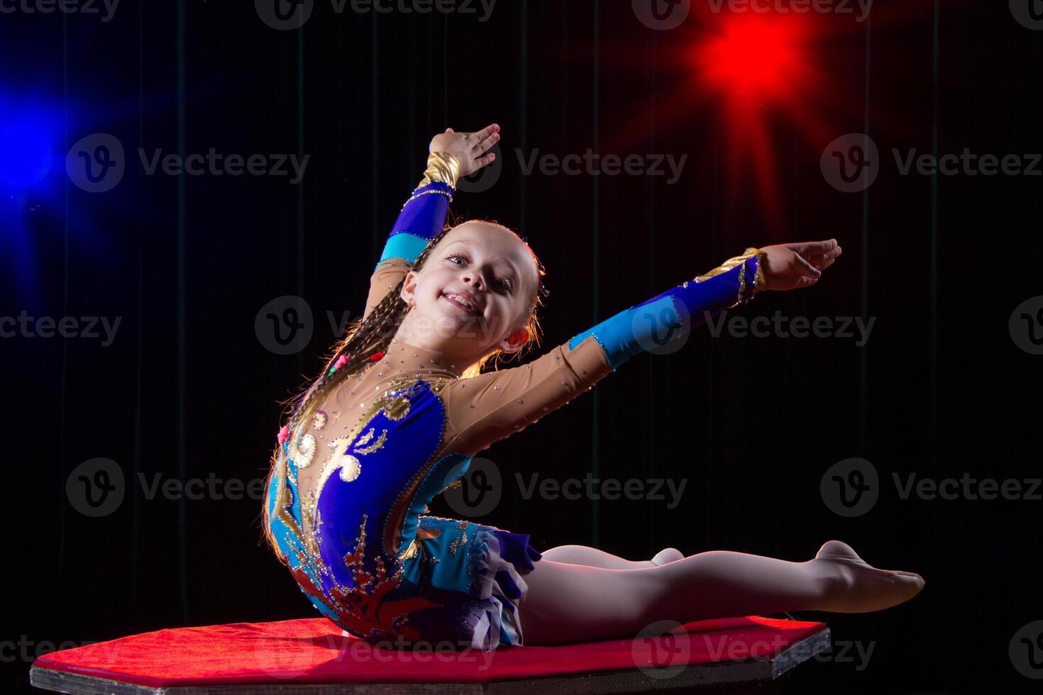 uma menina com uma flexível corpo. executa uma circo artista. circo ginasta. balanceamento agir. a criança executa a acrobático truque foto