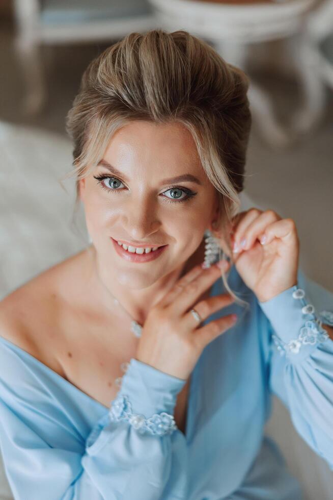 lindo, jovem, perfeito modelo noiva dentro uma branco renda vestir senta dentro a sala, quarto dentro a manhã, colocando a brinco em dela orelha. Casamento fotografia, retrato, conceito. foto