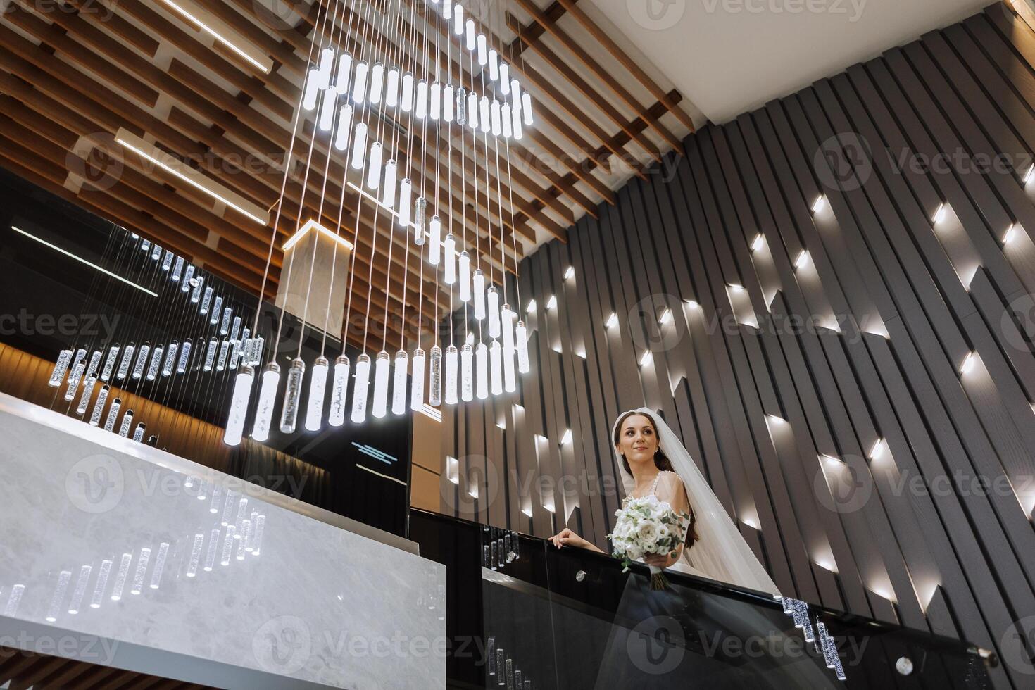 uma lindo noiva dentro uma vestir com uma grandes trem é em pé em a escadaria. branco Casamento vestir. lindo interior. foto