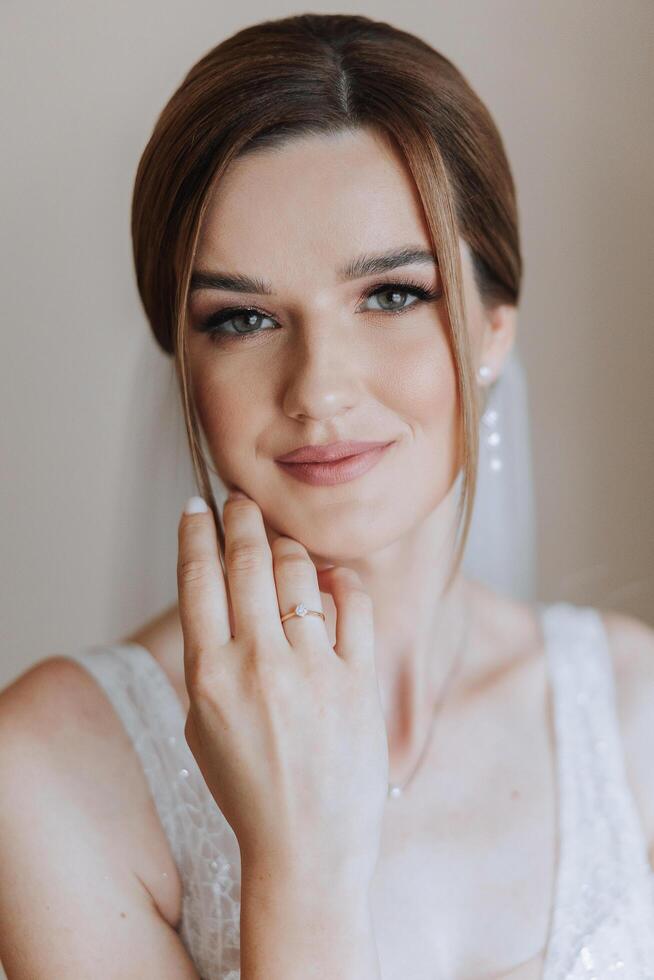 retrato do a noiva dentro a hotel sala. uma lindo jovem menina é vestido dentro uma branco Casamento vestir. moderno Casamento Penteado. natural inventar. foto