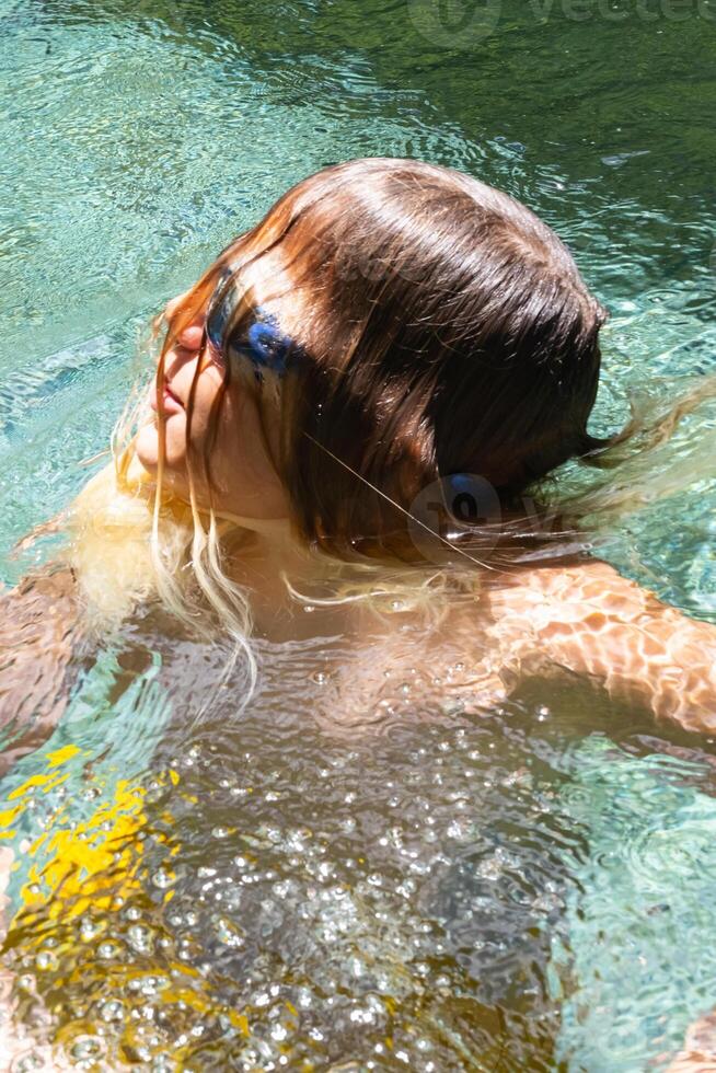 retrato do engraçado Adolescência com cabelo através face dentro natação piscina. foto