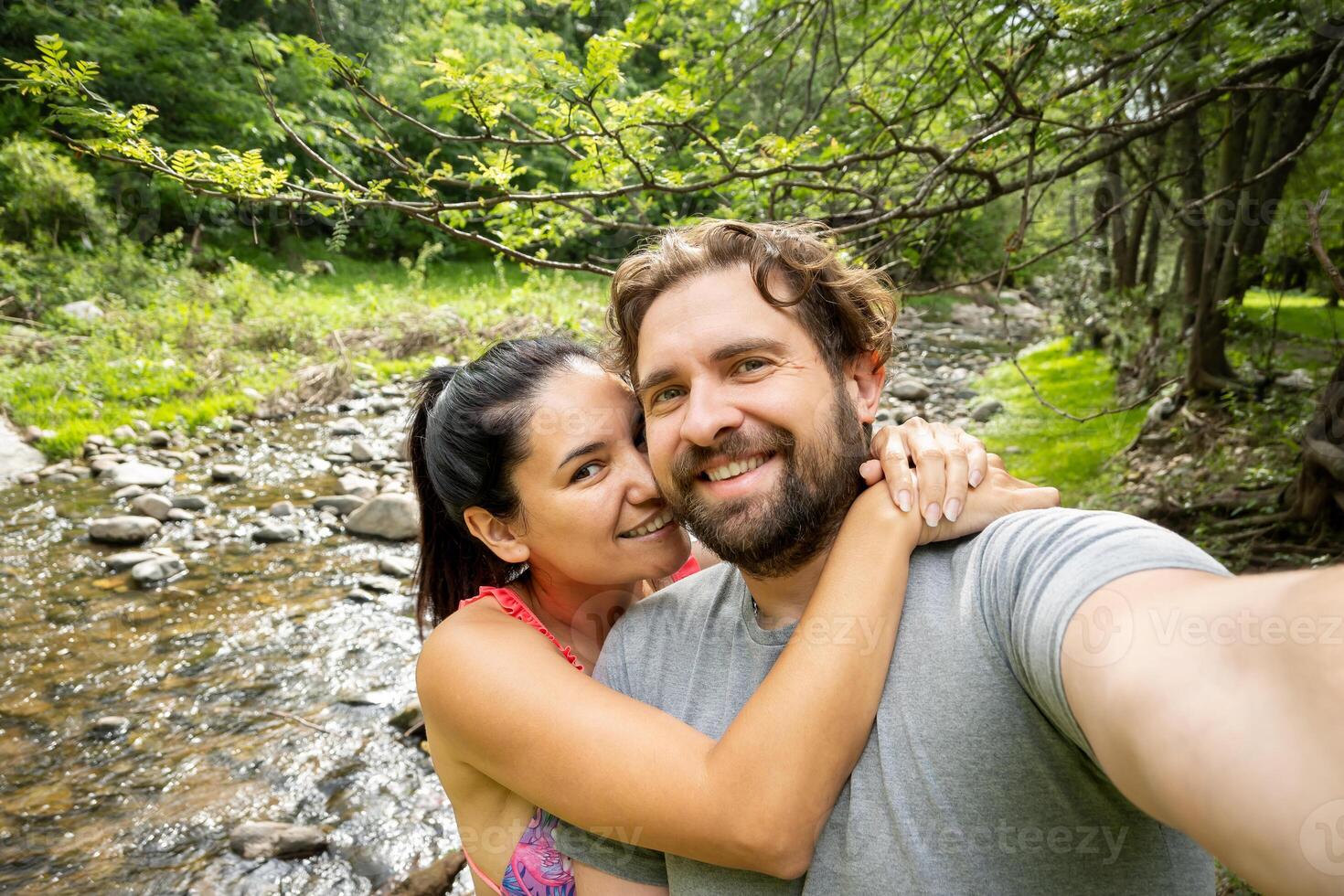 latim casal leva uma selfie em a bancos do uma rio dentro Argentina. elas estão feliz e abraçado. foto