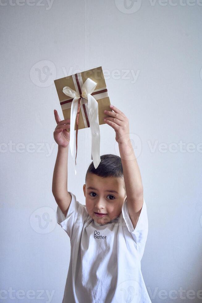 uma pequeno Garoto detém uma construir presente certificado dentro dele mãos foto