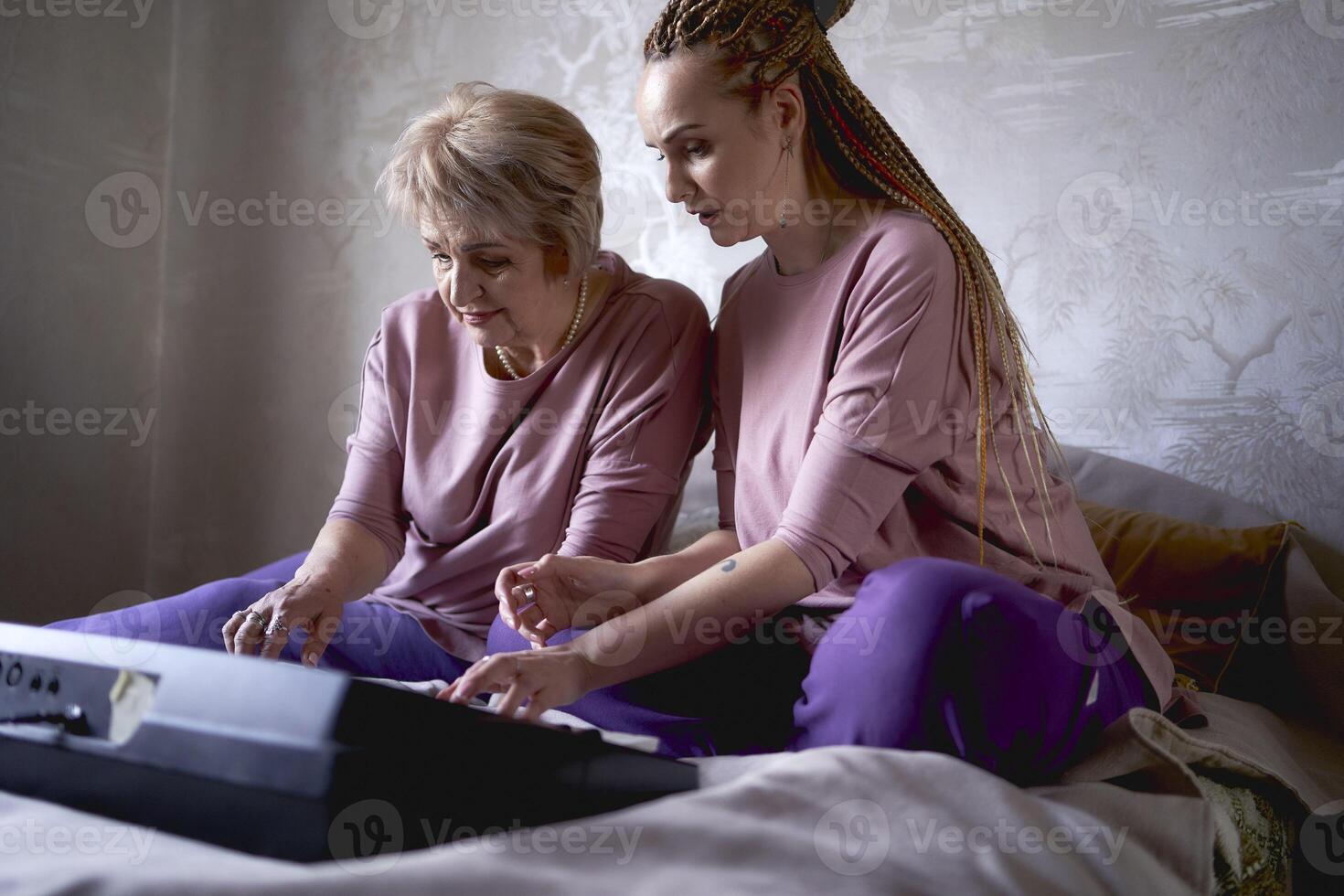 uma 60 anos mãe e uma 40 anos filha jogar a teclado juntos em a cama às casa foto