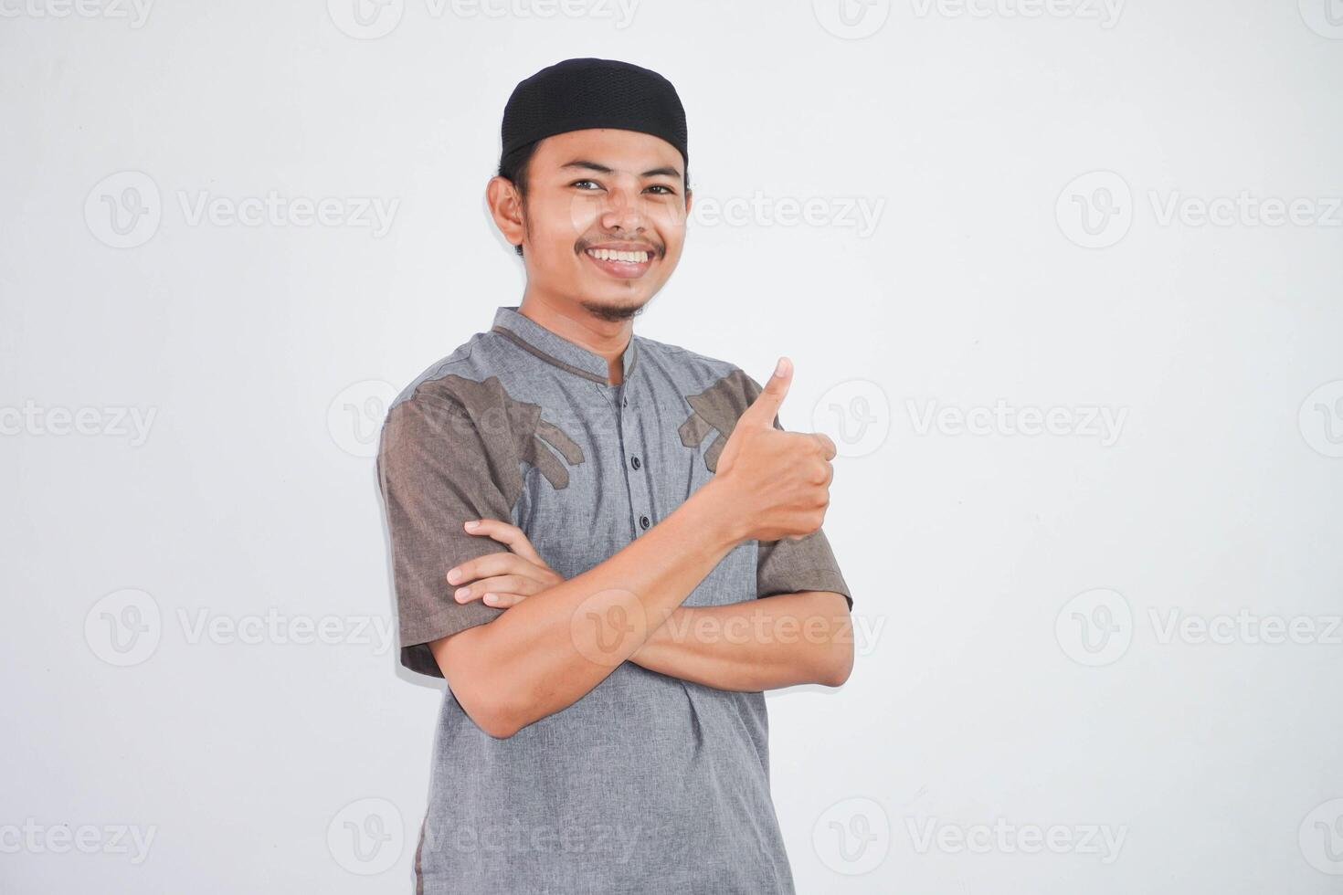 sorridente ou feliz jovem muçulmano homem mostrando mão polegares acima vestindo cinzento muçulmano roupas isolado em branco fundo foto