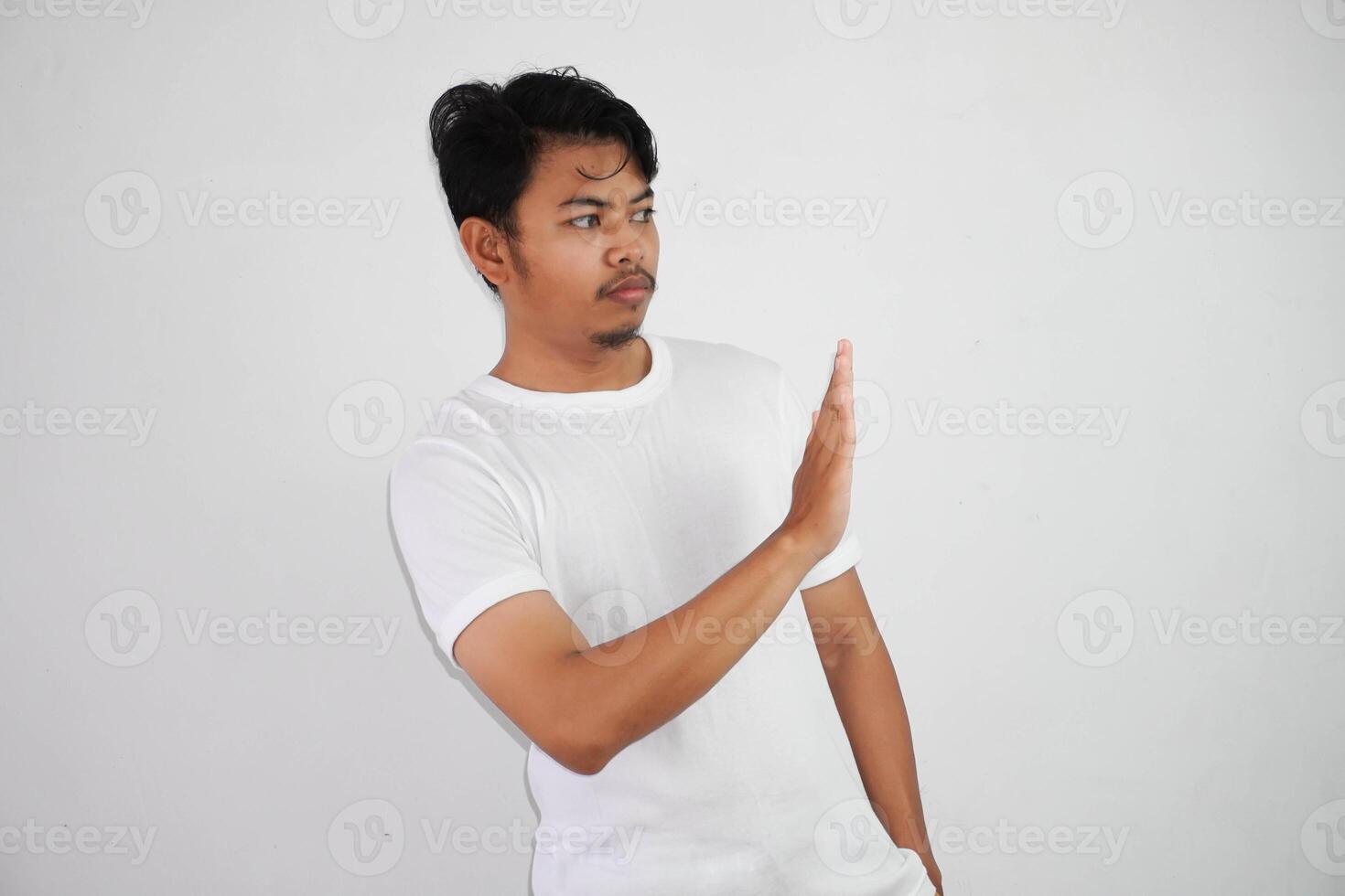 descontente bonito jovem ásia homem vestindo branco t camisa mostrando Pare placa isolado em branco fundo foto