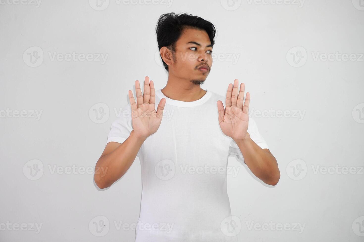 sério jovem ásia homem mostrando Pare gesto, demonstrando negação placa vestindo branco t camisa isolado em branco fundo foto