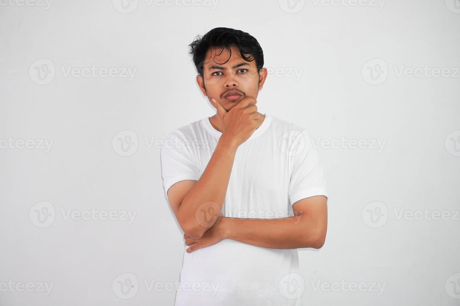 pensando jovem ásia homem segurando queixo pensando gesto, olhando para idéia vestindo branco t camisa isolado em branco fundo foto