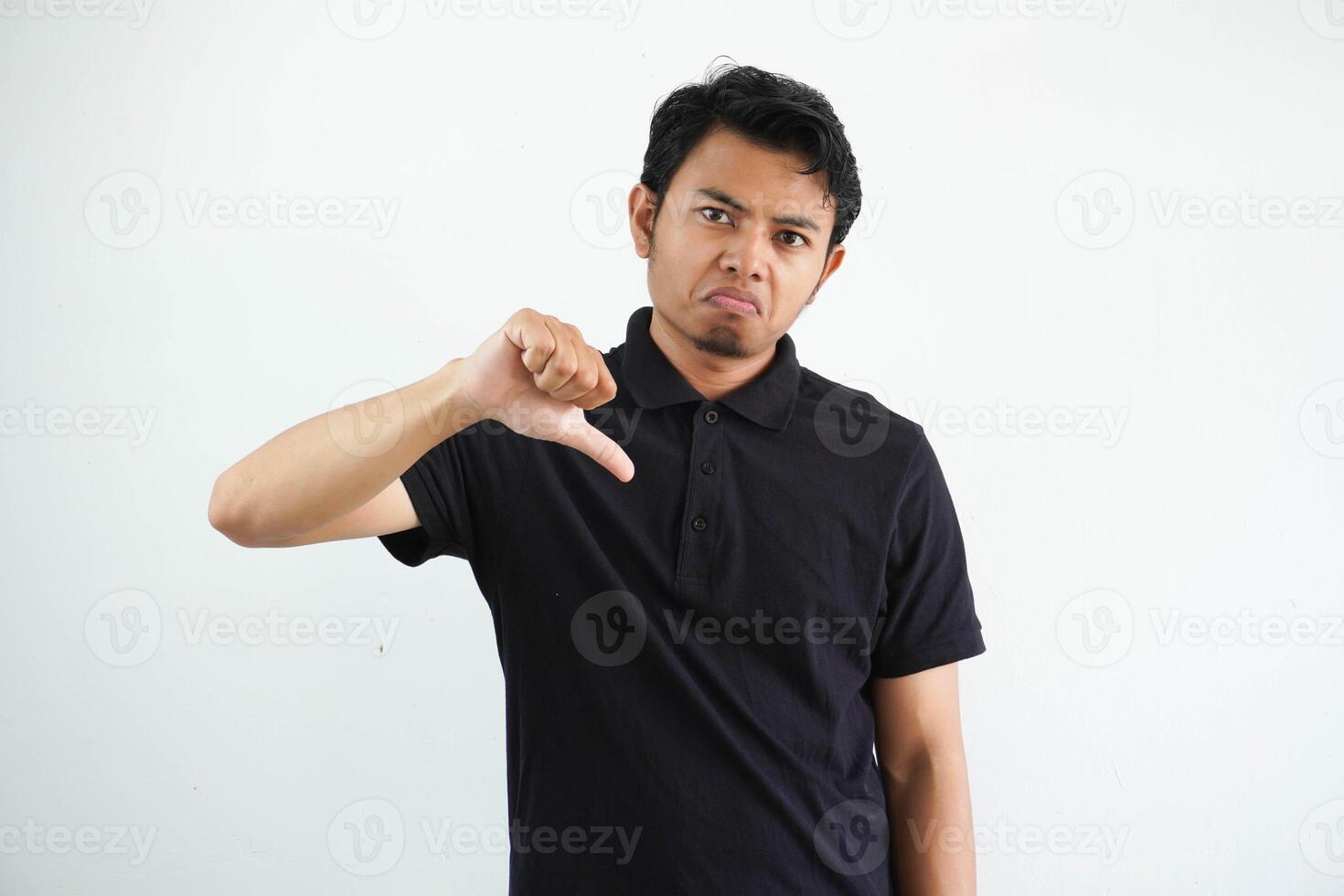jovem ásia homem mostrando polegar baixa placa com negativo expressão vestindo Preto pólo t camisa isolado em branco fundo foto