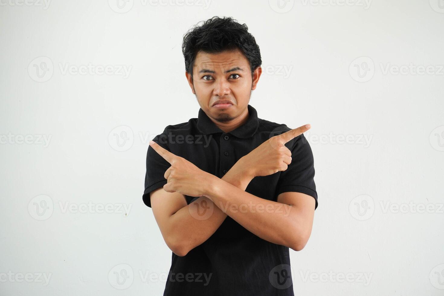 jovem ásia homem dentro uma Preto pólo, branco estúdio pontos de lado, é tentando para escolher entre dois opções. foto