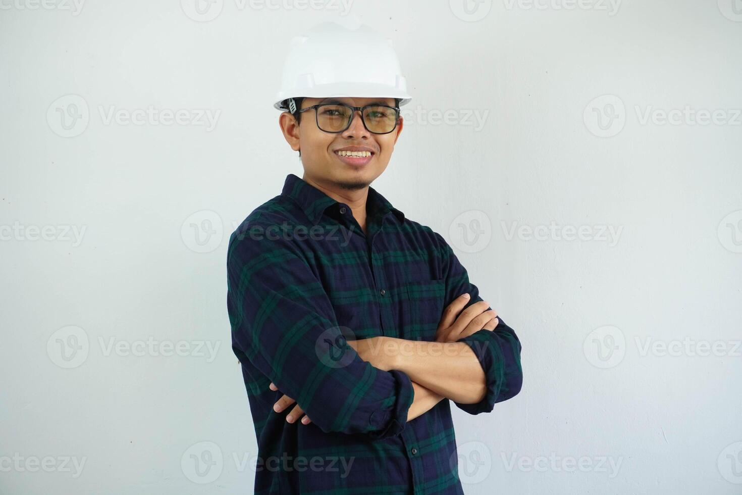 jovem ásia homem é engenheiro vestindo capacete em pé com cruzado braços e sorridente com confiante, arquiteto ou contratante, trabalhador ou trabalho, industrial conceito. foto