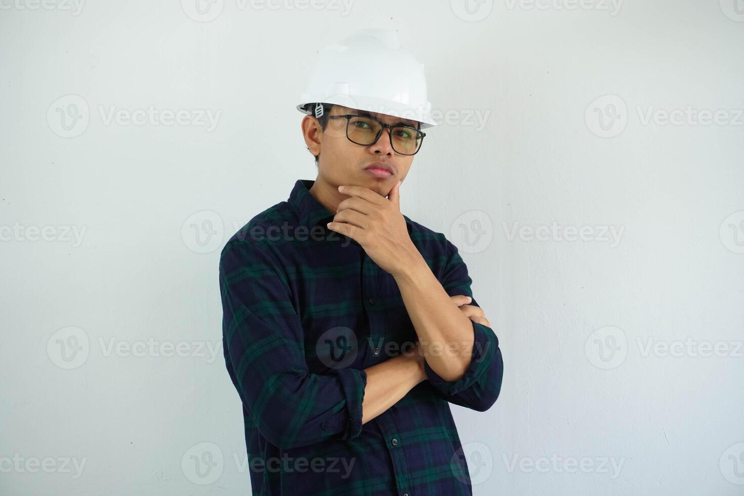 jovem ásia masculino engenheiro tocante dele queixo mostrando dúvida gesto dentro branco capacete olhando às Câmera isolado em branco fundo foto