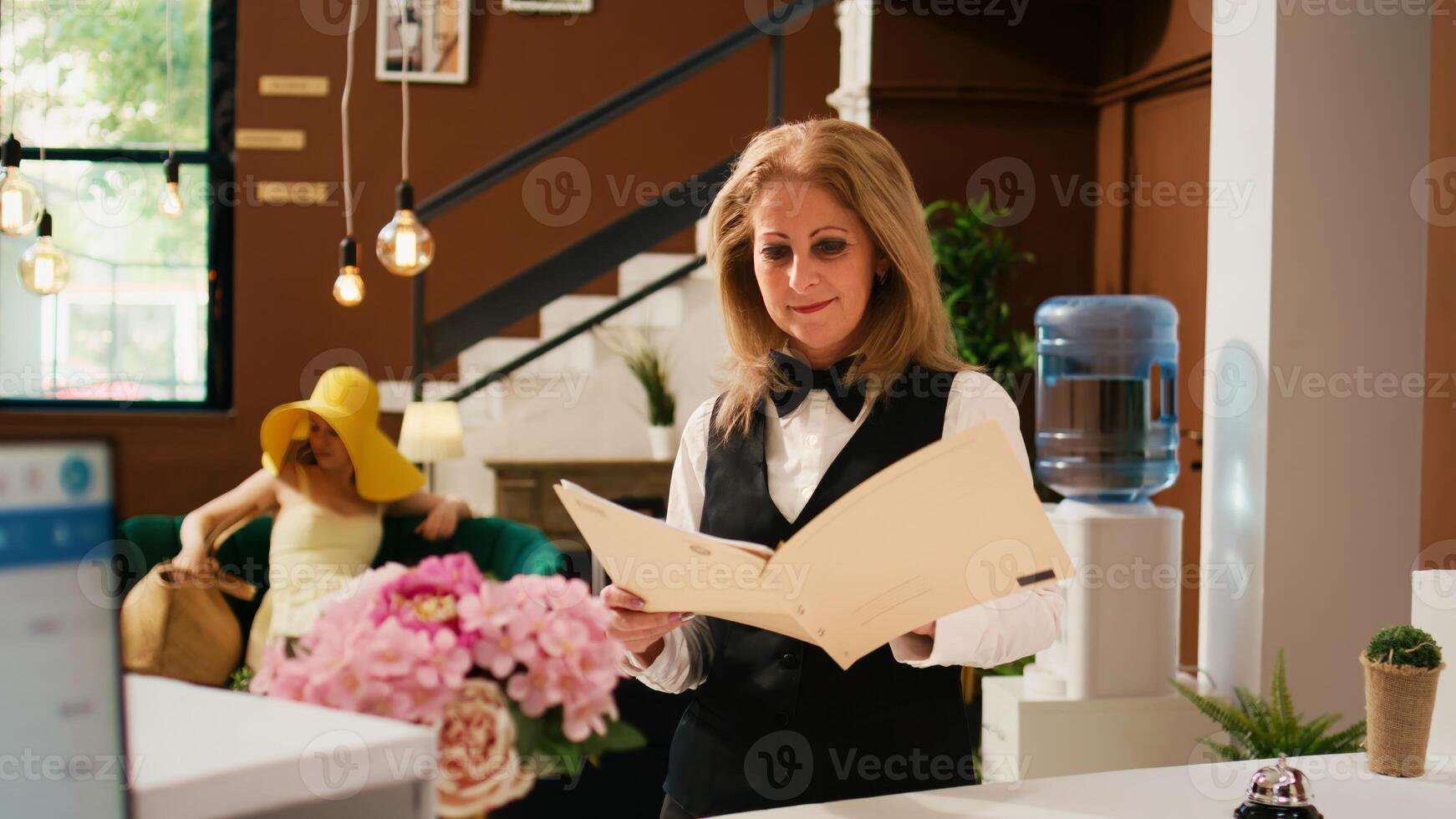 funcionários trabalhando com reservas formulários, verificação alojamento quarto reserva às hotel frente escrivaninha. mulher recepcionista preparando para bem-vinda convidados às luxo tropical verão recorrer. foto