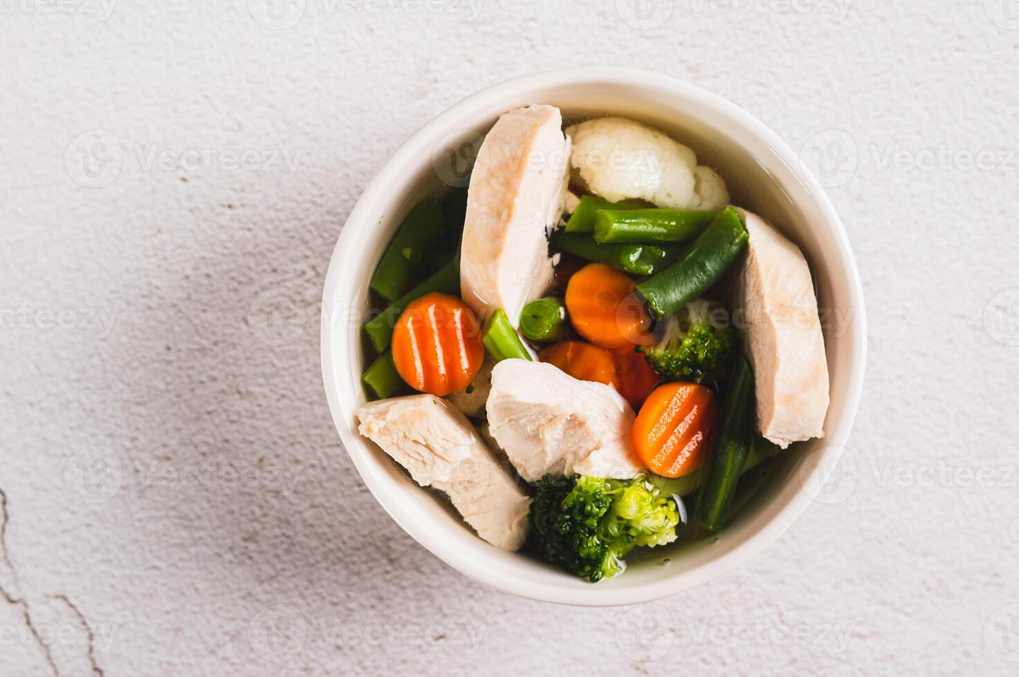 fechar acima do sopa com frango, couve-flor, brócolis, cenouras e verde feijões dentro uma tigela topo Visão foto