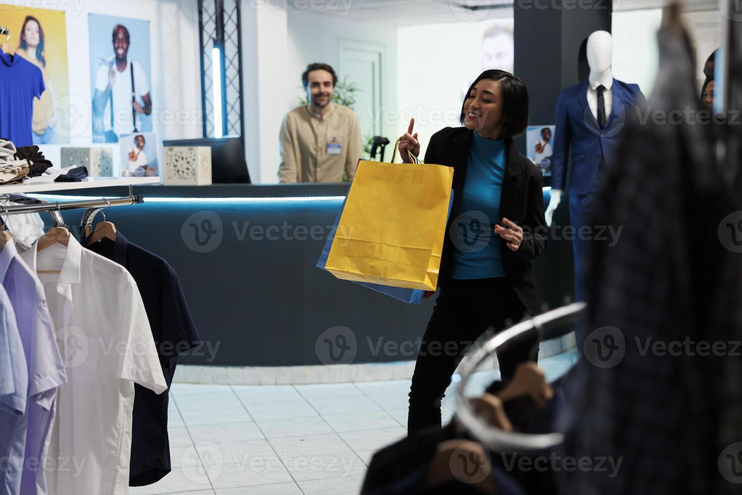 sorridente alegre ásia mulher dançando com pacotes dentro roupas loja depois de bem sucedido compras. feliz cliente segurando compras e tendo Diversão depois de comprando na moda vestuário foto