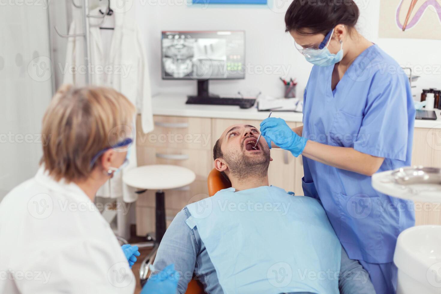 hospital enfermeira dentro médico uniforme olhando para dentro doente paciente boca analisando dentes saúde preparando para estomatológico cirurgia. estomatologista médicos trabalhando dentro ortodôntico clínica foto