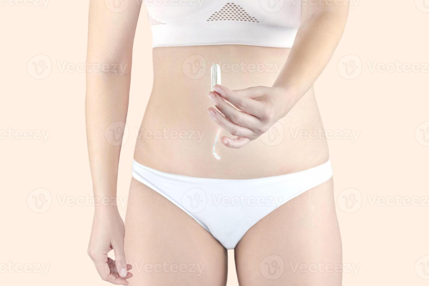 mulher segurando uma menstruação algodão tampão dentro dela mão, dentro branco roupa íntima foto