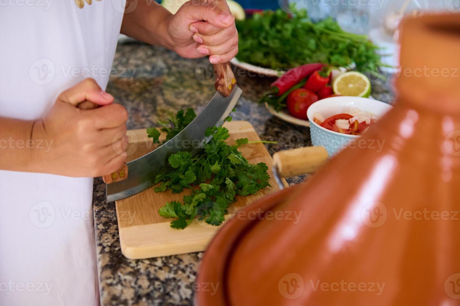 chef mãos cortar salsinha e coentro verde ervas para tempero uma tradicional marroquino prato - legumes dentro tagine foto