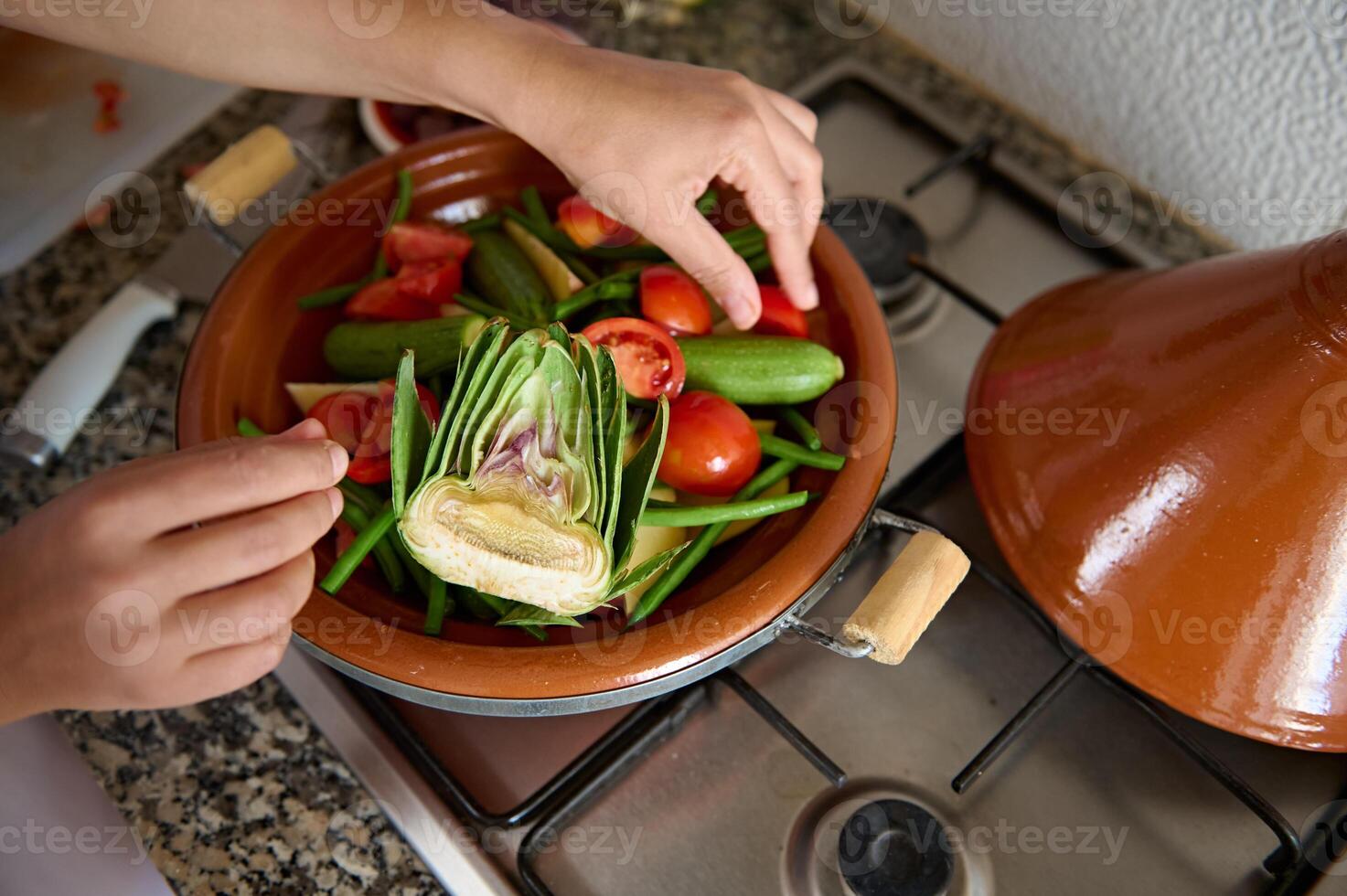 Visão a partir de acima do dona de casa mãos colocando ingredientes enquanto cozinhando tagine com delicioso orgânico legumes foto