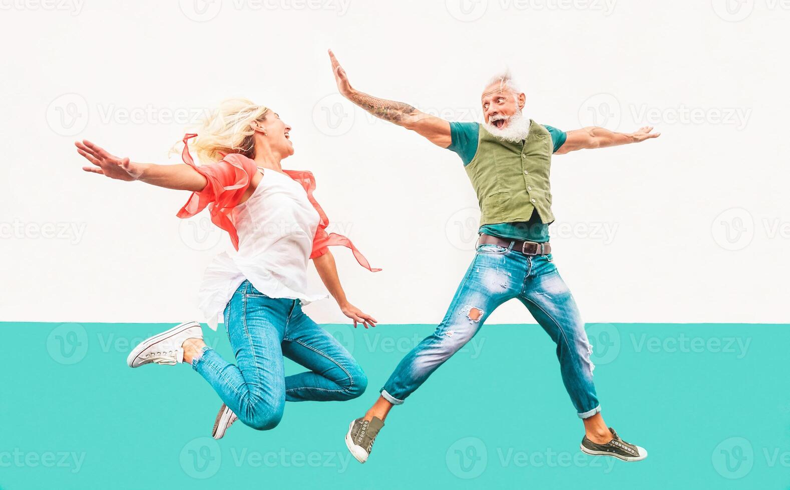 feliz louco casal pulando juntos ao ar livre - maduro na moda pessoas tendo Diversão a comemorar e dançando lado de fora - conceito do felicidade, liberdade, despreocupado, amor e relação foto