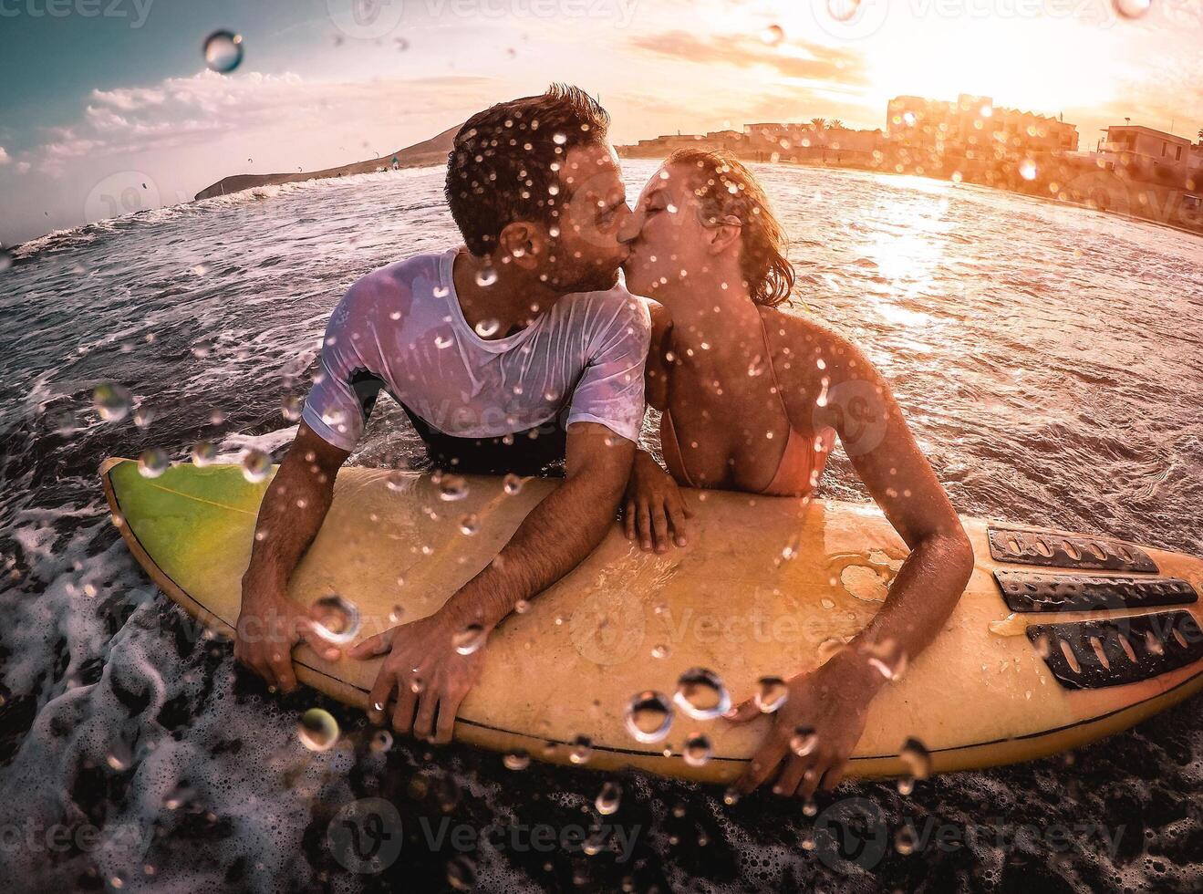 feliz romântico casal se beijando enquanto surfar dentro a oceano - desportivo surfistas bodyboard tendo uma concurso momento dentro a água - extremo esporte, amor, relação e saudável estilo de vida conceito foto