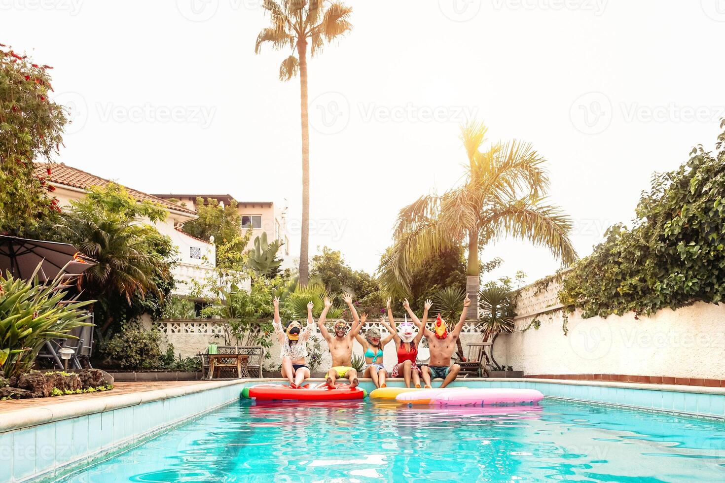 grupo feliz amigos vestindo mascarar fazer piscina festa - jovem pessoas tendo Diversão a comemorar evento dentro exclusivo natação piscina verão tropical período de férias - amizade e juventude feriados estilo de vida conceito foto